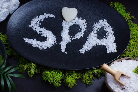 Spa word written in white bath salt on a black dish, bath salt with spatula and green moss.の写真素材