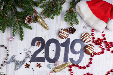 Figures 2019, cookies and Christmas decorations with a Christmas tree with a red cap on a light background. New year concept. Greeting christmas card. Flat lay.の写真素材