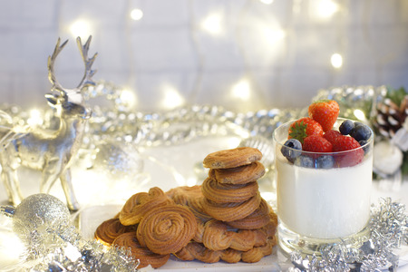 Panakota with berries in a glass, cookies and silver deer, garlands and sparkles decorate the room, Christmas mood.の写真素材