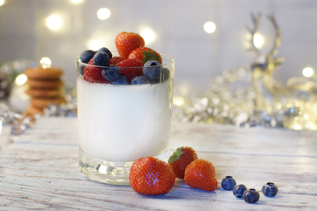 Panakota with berries in the glass, cookies and silver deer, garlands and tinsel decorate the room, New Year's mood.の写真素材