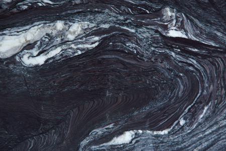 Stunning light pattern on a dark natural stone, which is called quartzite Rosso Luana.の写真素材