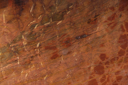 Natural stone of red color with yellow and burgundy streaks and cracks.の写真素材