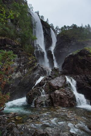 Travel to Norway, a high waterfall falls into the river and flows down from the rocksの写真素材