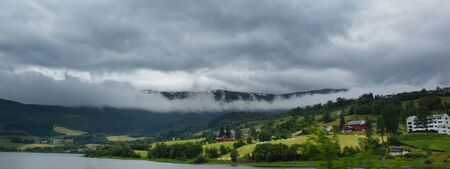 Travel to Norway, a panorama of the coast with houses and fields on the shore of the fjord.の写真素材