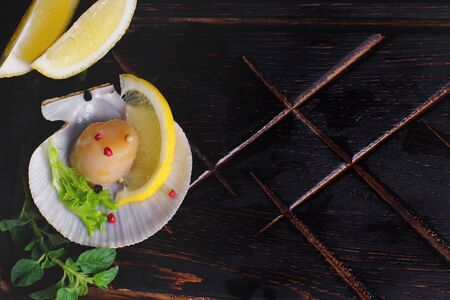 Top view on scallops fillet in its shell with spices and lemon.の写真素材