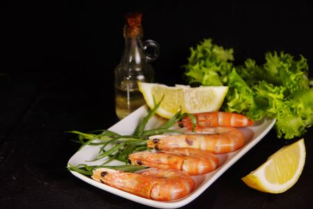 Raw shrimps lie on a plate next to other ingredientsの写真素材