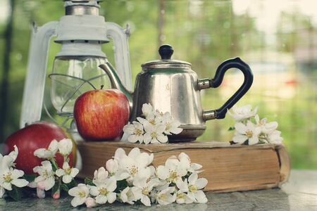 Still life with apples, a teapot and delicate flowers on the table.の写真素材