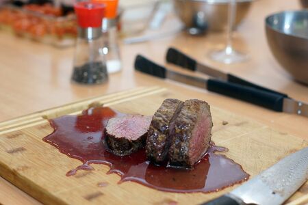 Wooden board with slices of hot beef tenderloin in a pool of blood.の写真素材