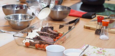 Dish with beef tenderloin, cherry tomatoes and sauce, the cook is pouring food on the sauce.の写真素材