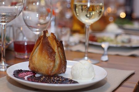 Dough cake on a plate with a ball of ice cream and sauce is on a beautifully served table.の写真素材