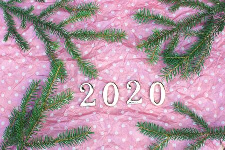Figures 2020 on a pink background with white peas surrounded by branches of a green Christmas tree.