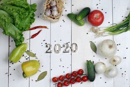 Golden numbers 2020 lie in the center of different vegetables on a white board background.の写真素材