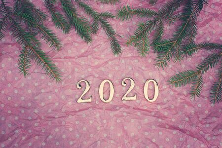 Figures 2020 on a pink background with white peas, branches of a green Christmas tree on top.の写真素材