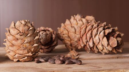 A pine cone and a handful of pine nuts lie on a wooden table.の写真素材
