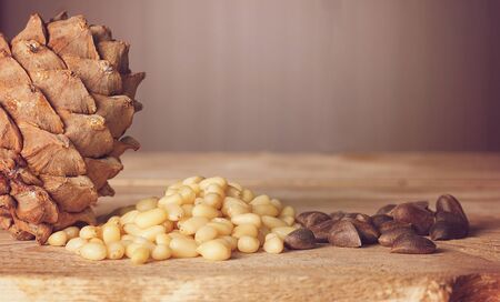 Cedar cone and pine nuts lie on a wooden table.の写真素材