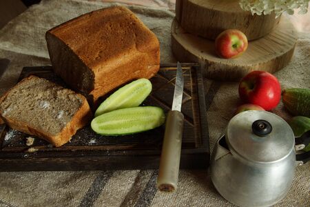 Still life with fresh bread and salt, next to a green cucumber from the garden, rustic style.の写真素材