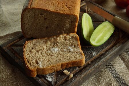 Still life with mouth-watering fresh bread and salt, next to a fresh cucumber from a vegetable garden , rustic style.の写真素材