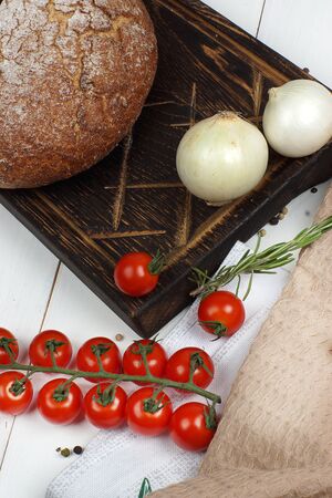 A set of products from bread, onions and cherry tomatoes on the table before cooking.の写真素材