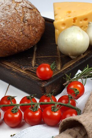 A set of products from fresh, crisp bread, cheese, onions and cherry tomatoes on the table before cooking.の写真素材