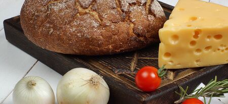 A set of products from fresh, crisp bread, cheese, onions and cherry tomatoes on a white table before cooking.の写真素材