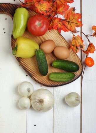 Top view on vegetables on a white wooden table and near orange autumn maple leaves.の写真素材