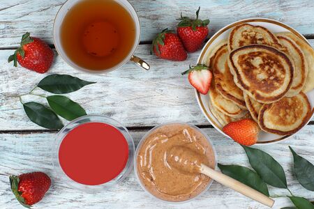 Whipped honey in a jar on a light wooden table next to strawberries and fried fritters, your advertisement with text.の写真素材