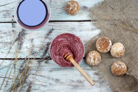 Whipped honey in saturated burgundy color and a spoon spindle on the table next to a bouquet of lavender and gingerbread cookies, top view.の写真素材