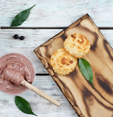 Pink cream honey with a spoon spindle on a table, near cookies on a board, top view.の写真素材