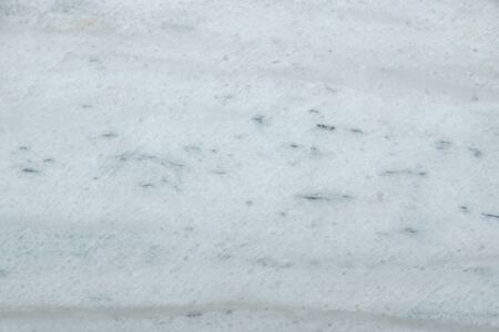 A polished slab of white marble with gray blurry stripes and dots called Nestos Beige.の写真素材