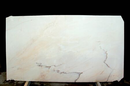A polished slab of white and beige marble with stripes is called Bianco Rosa Portugalo.の写真素材