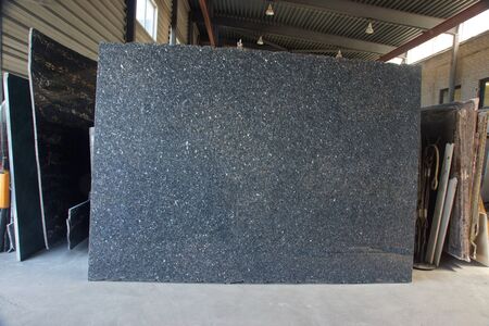 A large gray granite slab stands in a warehouse of natural stone, this one is called Blue Pearl.の写真素材
