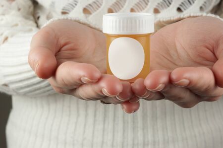 Beautiful female hands of a European hold a jar of cream or balm on their palmsの写真素材