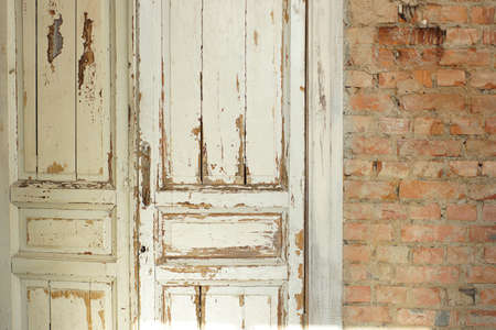 Old, white painted doors, closed, indoors with red brick walls.の写真素材