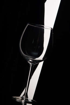 Empty wine glass bent over black and white background.の写真素材