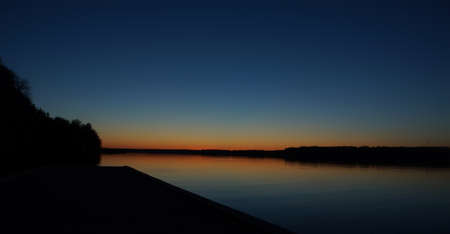 Last minutes of sunset with a strip of red sky over the lake.の写真素材
