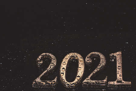 Metallic numbers 2021 in golden color covered with water droplets on a dark backgroundの写真素材