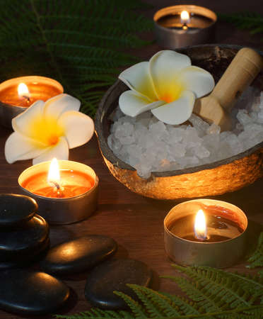 Black flat stones for hot massage against the background of burning candles and sets for SPA procedures.の写真素材