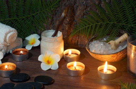 stones for hot massage are prepared on the table along with burning candles.の写真素材