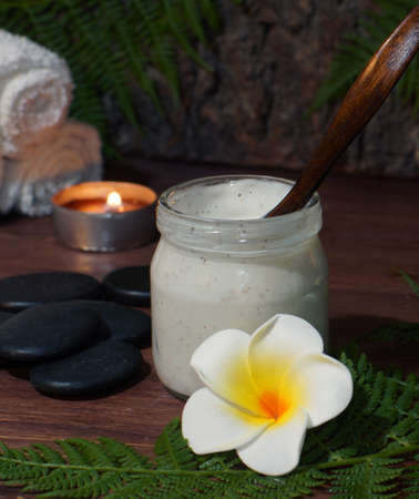 Body scrub in a jar against the background of burning candles and other spa accessories.の写真素材