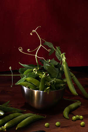 Green peas in pods and with leaves on a red background.の写真素材