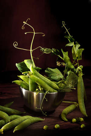 Green peas in pods and with leaves on a brown background.の写真素材