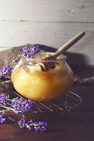 A jar of honey next to a lavender bouquet.の写真素材