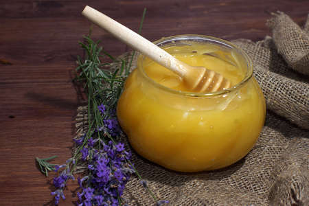 A jar of natural honey with a spindle spoon on a mat on the table.の写真素材