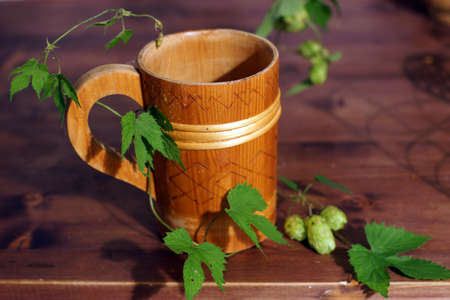 Beautiful wooden beer mug on the table with hop plant.の写真素材