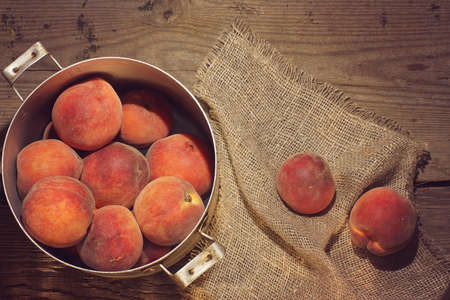 Peaches in a saucepan and small yellow flowers on the table.の写真素材