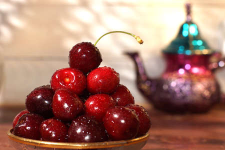 Dishes with bright juicy cherries and teapots in oriental style.の写真素材