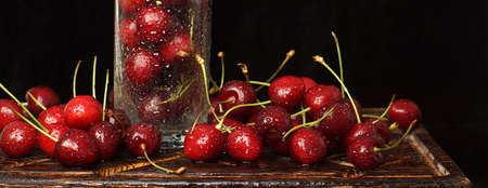 Ripe sweet cherries scattered near a glass with water droplets.の写真素材
