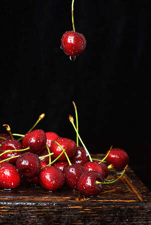 Juicy ripe cherry berry on a dark background over the same berries lying on the table.の写真素材