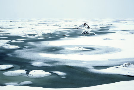 Spring melting of ice on the bay, beginning of spring, blue water shows through ice and white snow.の写真素材