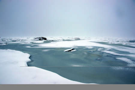 Spring melting of ice on the bay, beginning of spring, water shows through the ice.